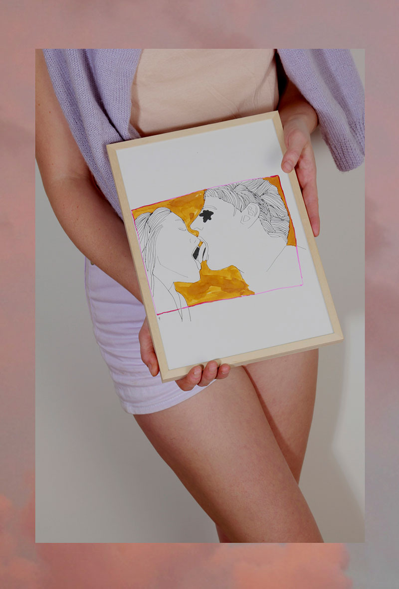 Een foto van Titia met een print van een illustratie van twee tongende mensen in haar handen.